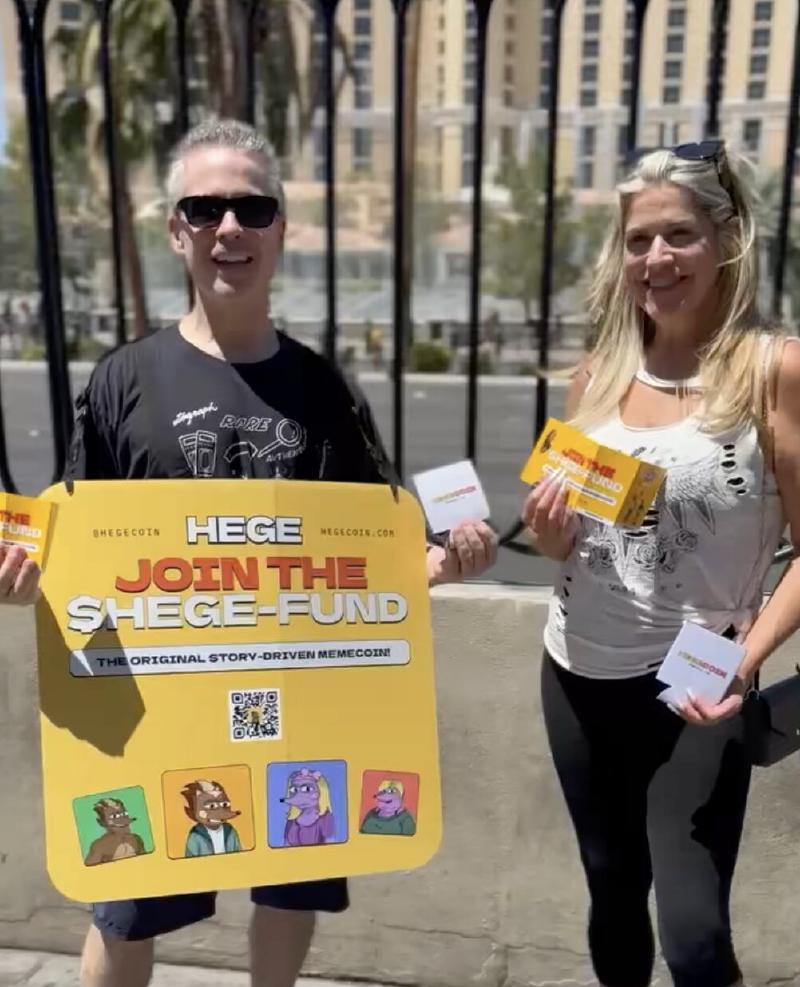 A man and a woman standing on a street i Las Vegas, holding up HEGE promotional material